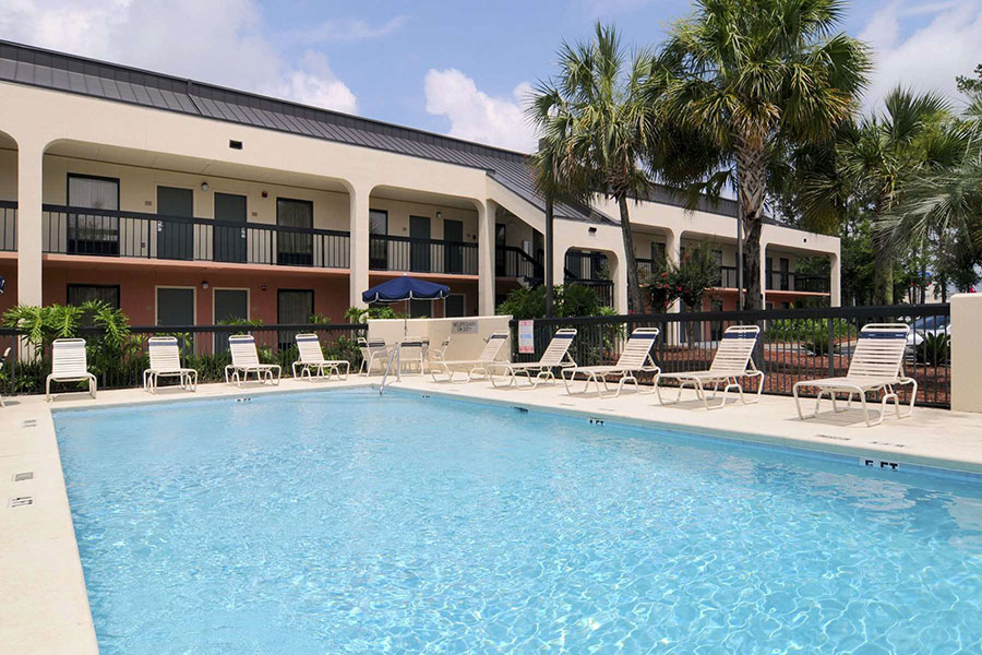 outdoor pool with chaise lounge chairs around at Baymont by Wyndham Tallahassee