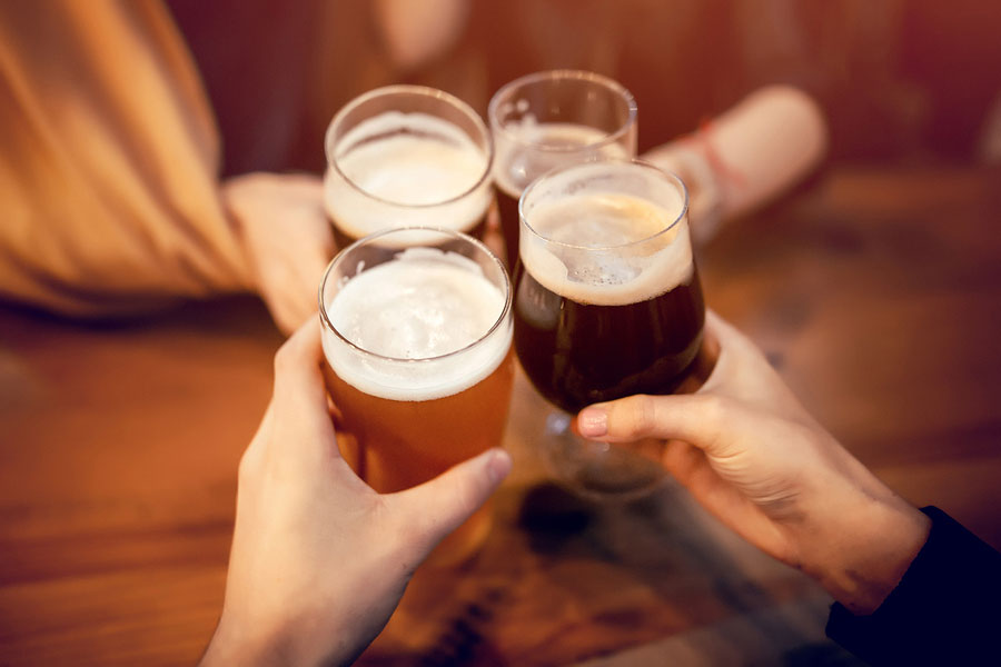 friends clinking and toasting with delicious craft beer in bar